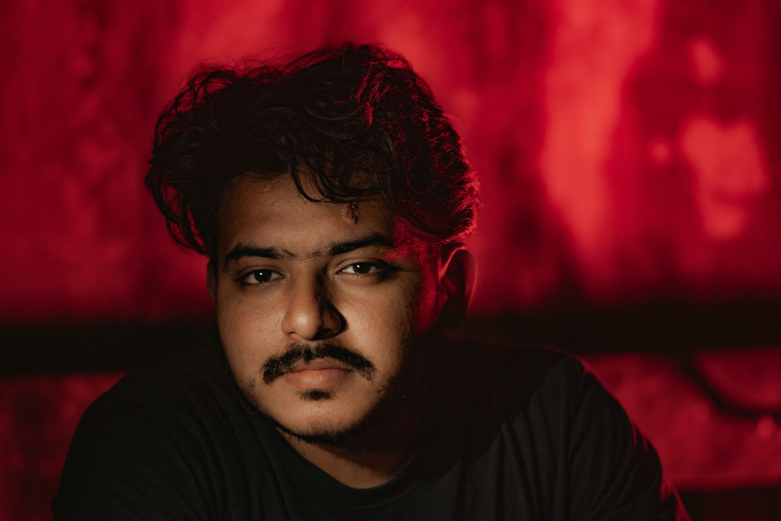 Expressive close-up portrait of a young man against a dramatic red background